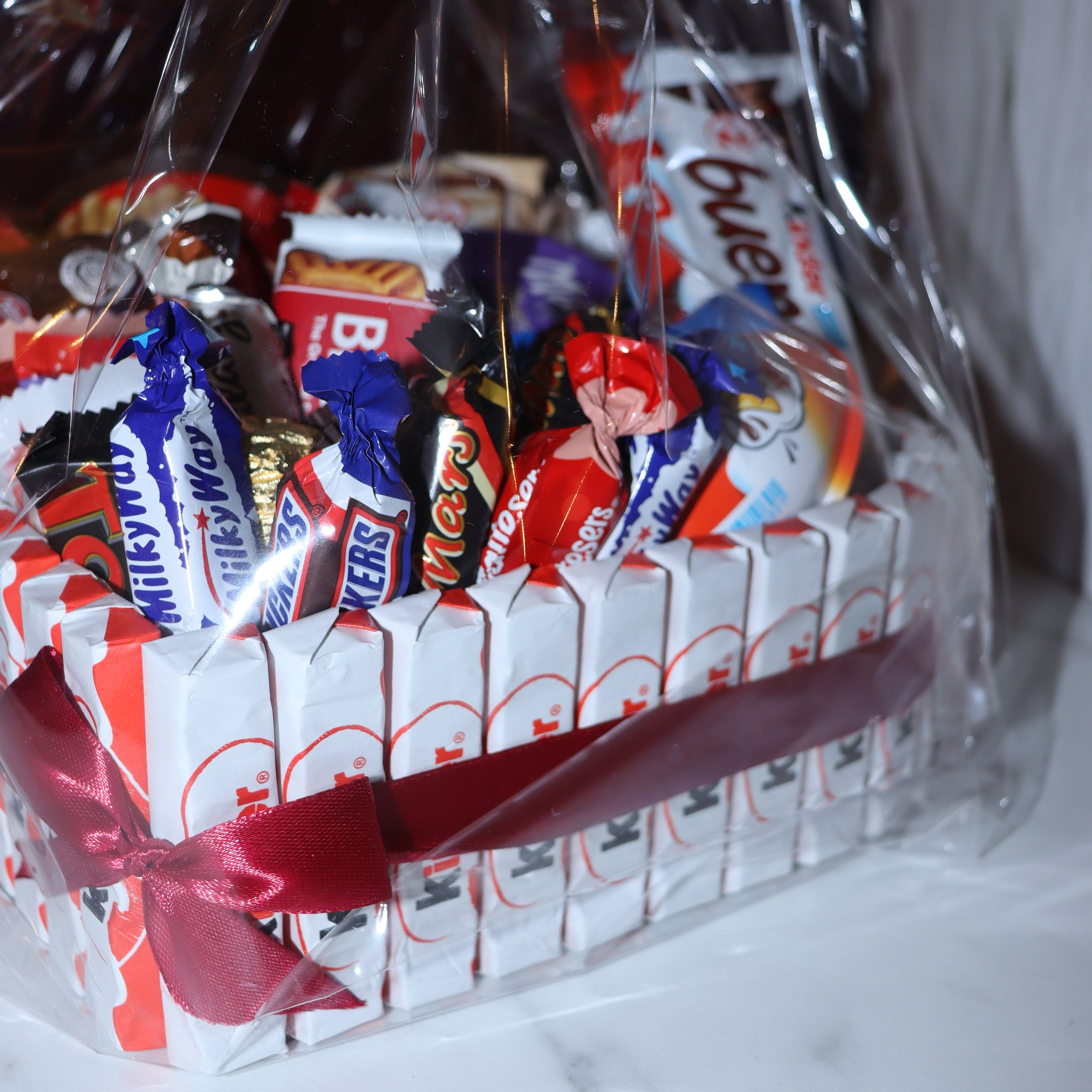 Photo rapprochée de la box cœur, montrant les Kinder entourée de ruban rouge