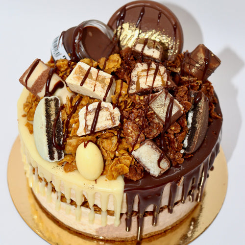Gros plan sur un entremets bi-goût au chocolat blanc et au Nutella, recouvert de cornflakes et d'autres chocolats blancs et au lait de toutes sortes.
