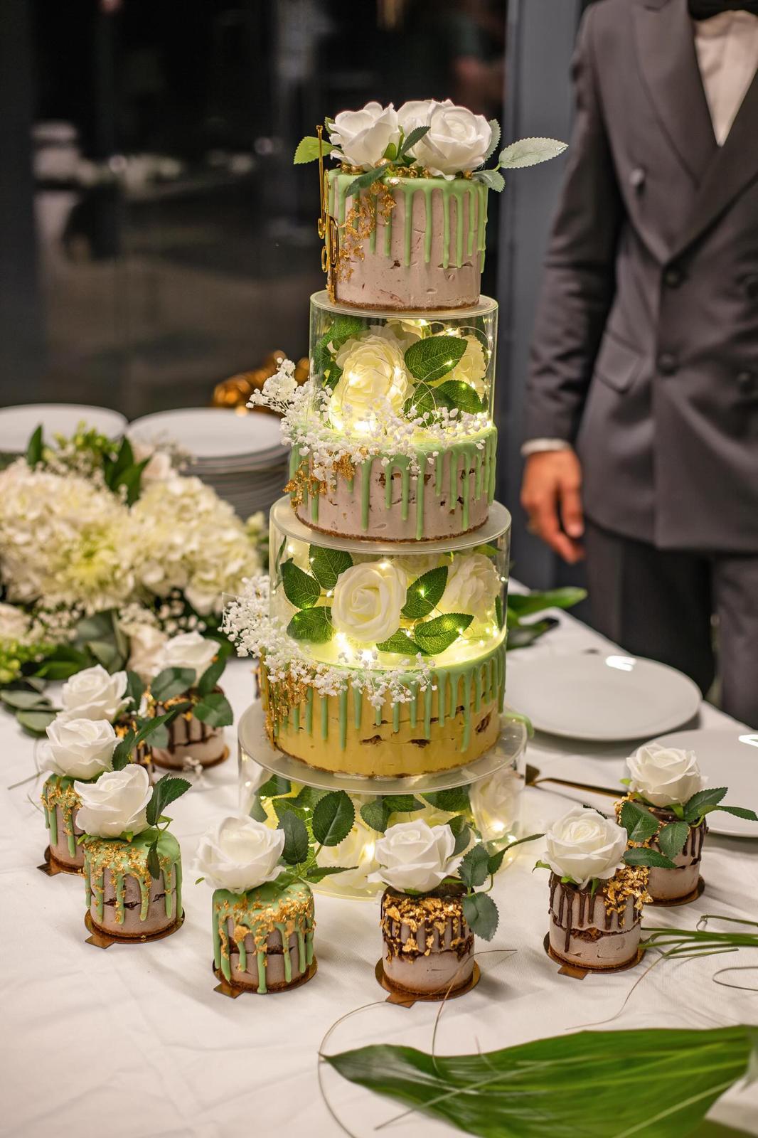 Photo d'une pièce montée, soigneusement posée au milieu de la table, entourée de plusieurs gâteaux glacés individuels.