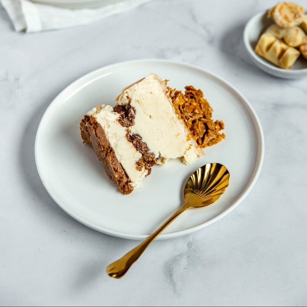 Une part d'un entremet coupé dans une assiette, accompagnée d'une cuillère dorée