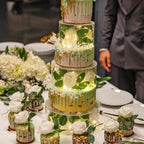 Photo d'une pièce montée illuminée par des lumières à l'intérieur, des gâteaux glacés individuels autour.