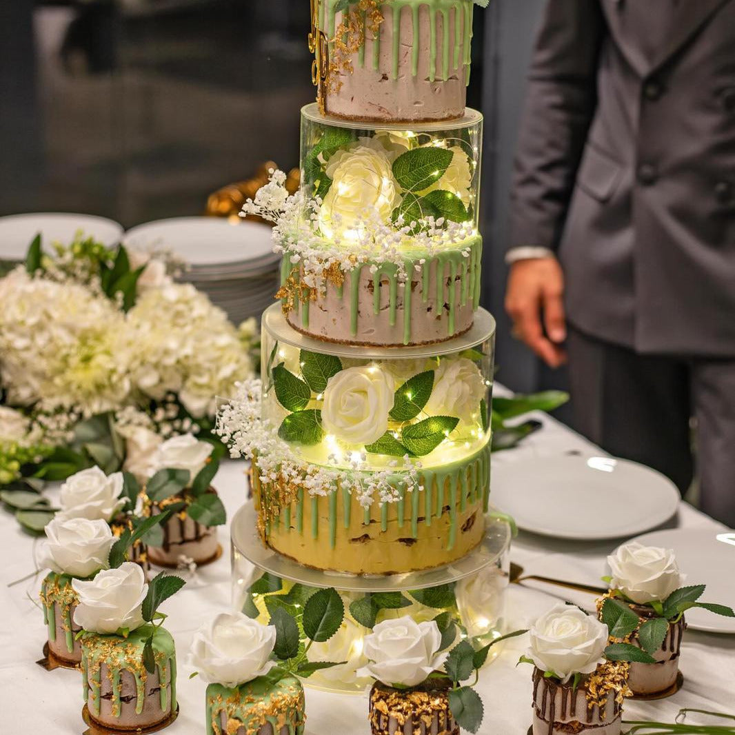 Photo d'une pièce montée illuminée par des lumières à l'intérieur, des gâteaux glacés individuels autour.