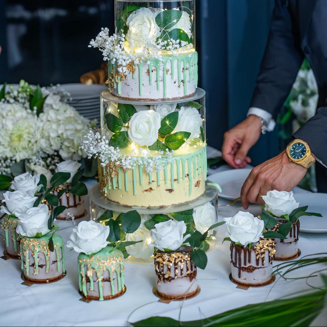 Photo d'une pièce montée illuminée par des lumières à l'intérieur, des gâteaux glacés individuels autour.